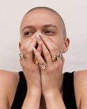 woman with hands over face wearing silver and gold rings